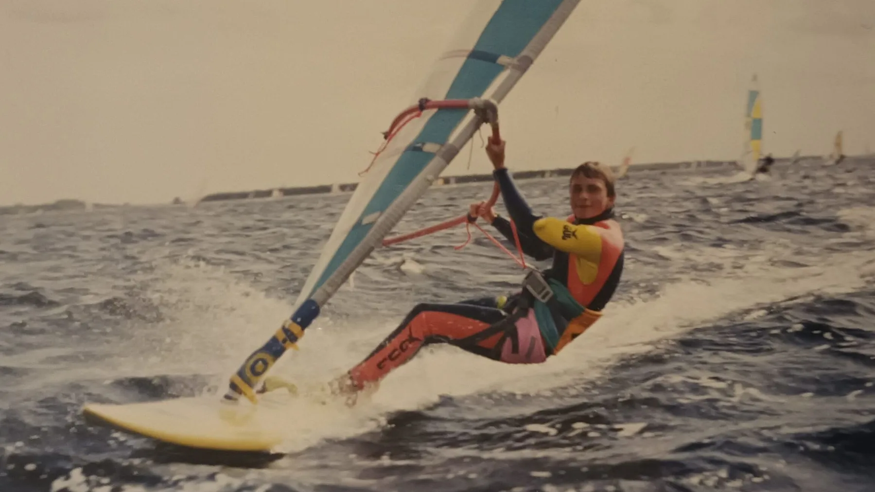 Windsurfer hangt in het tuig op een board uit de jaren tachtig