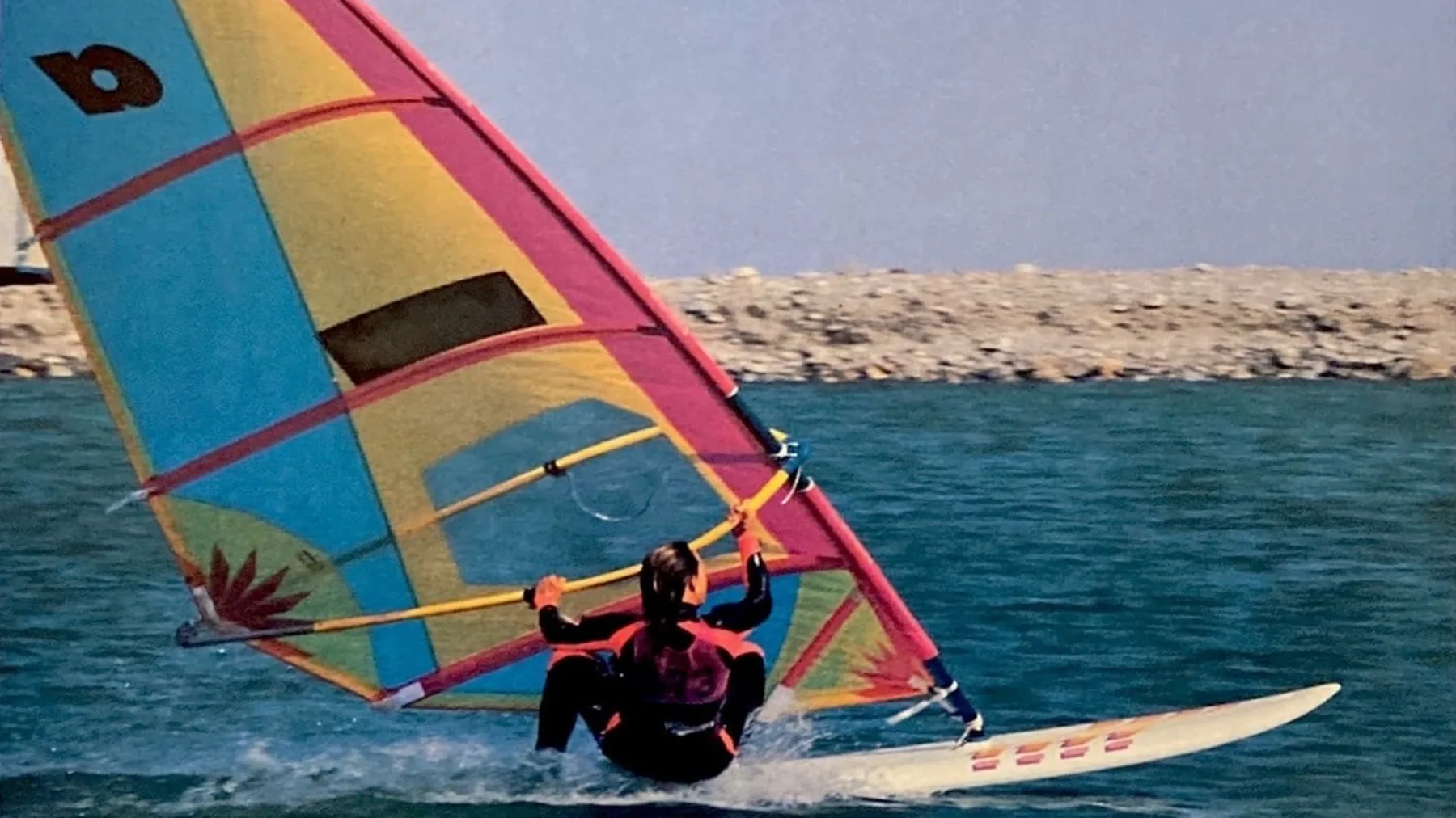 Vintage windsurfplank met kleurrijk zeil uit de jaren tachtig