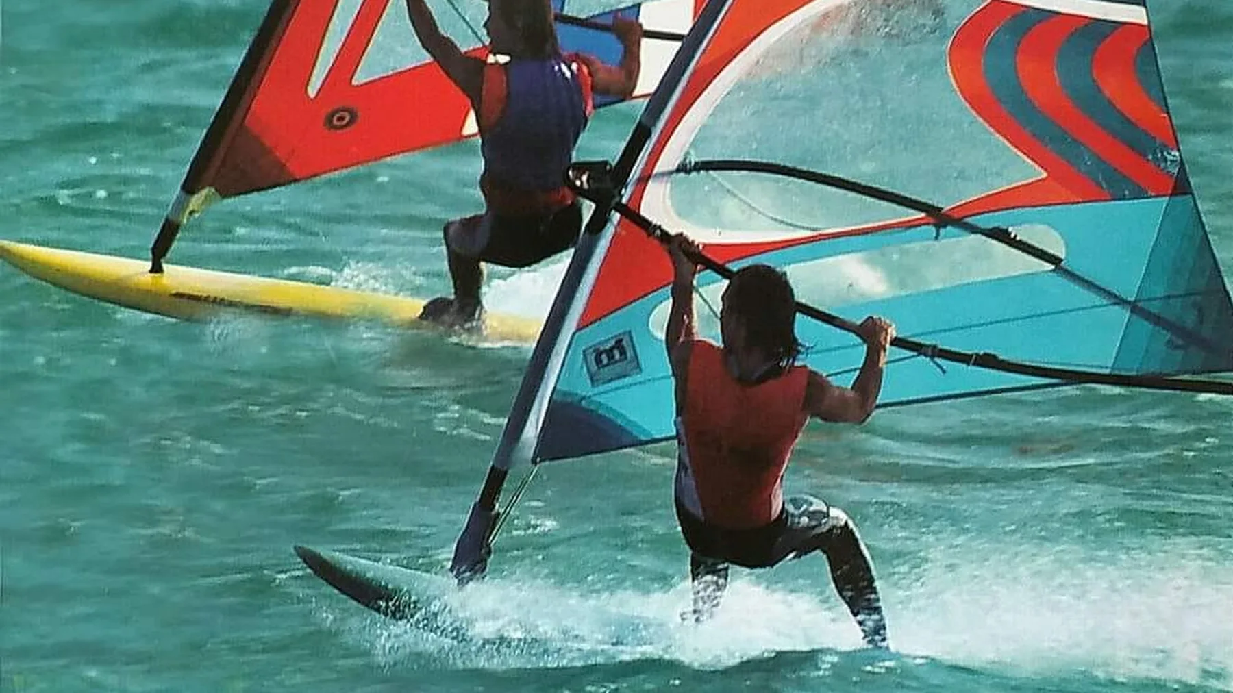 Twee windsurfers naast elkaar op helder water