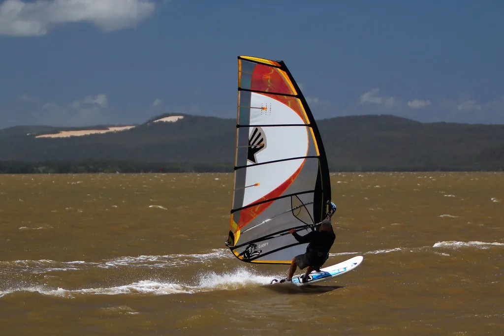 Windsurfer planeert in het trapeze op een moderne set met licht zeil